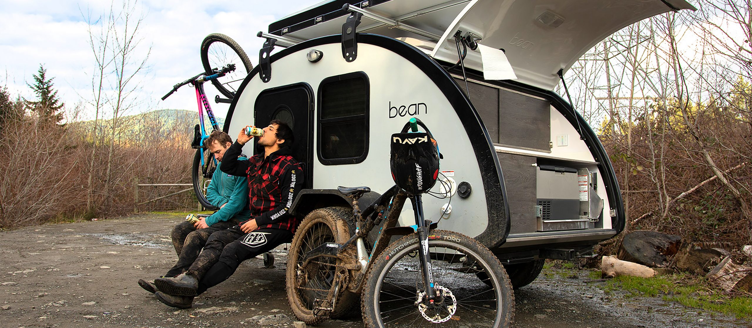 Professional Mountain Bikers rest on a teardrop trailer at the end of long day.