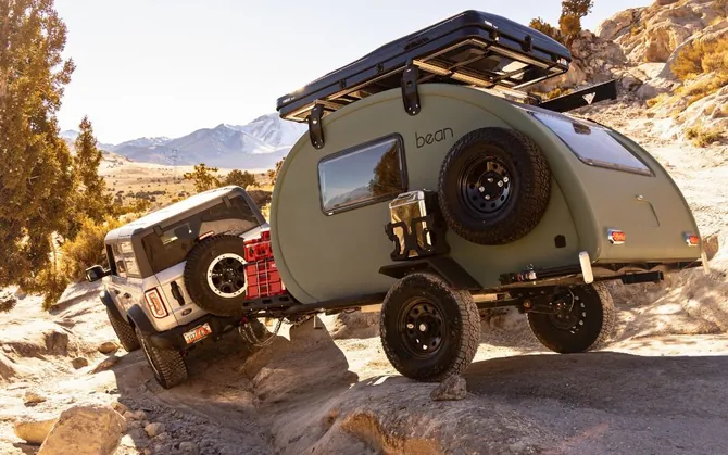 An olive green Bean towed over rock ledges on a desert trail