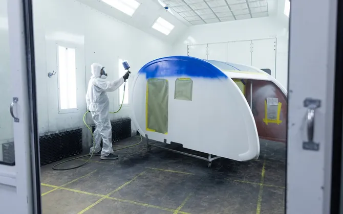 A technician spraying a Bean shell blue in the paint booth