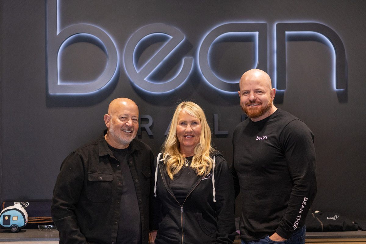 Mark, Cindy and Brian standing together beneath the lit Bean Trailer sign
