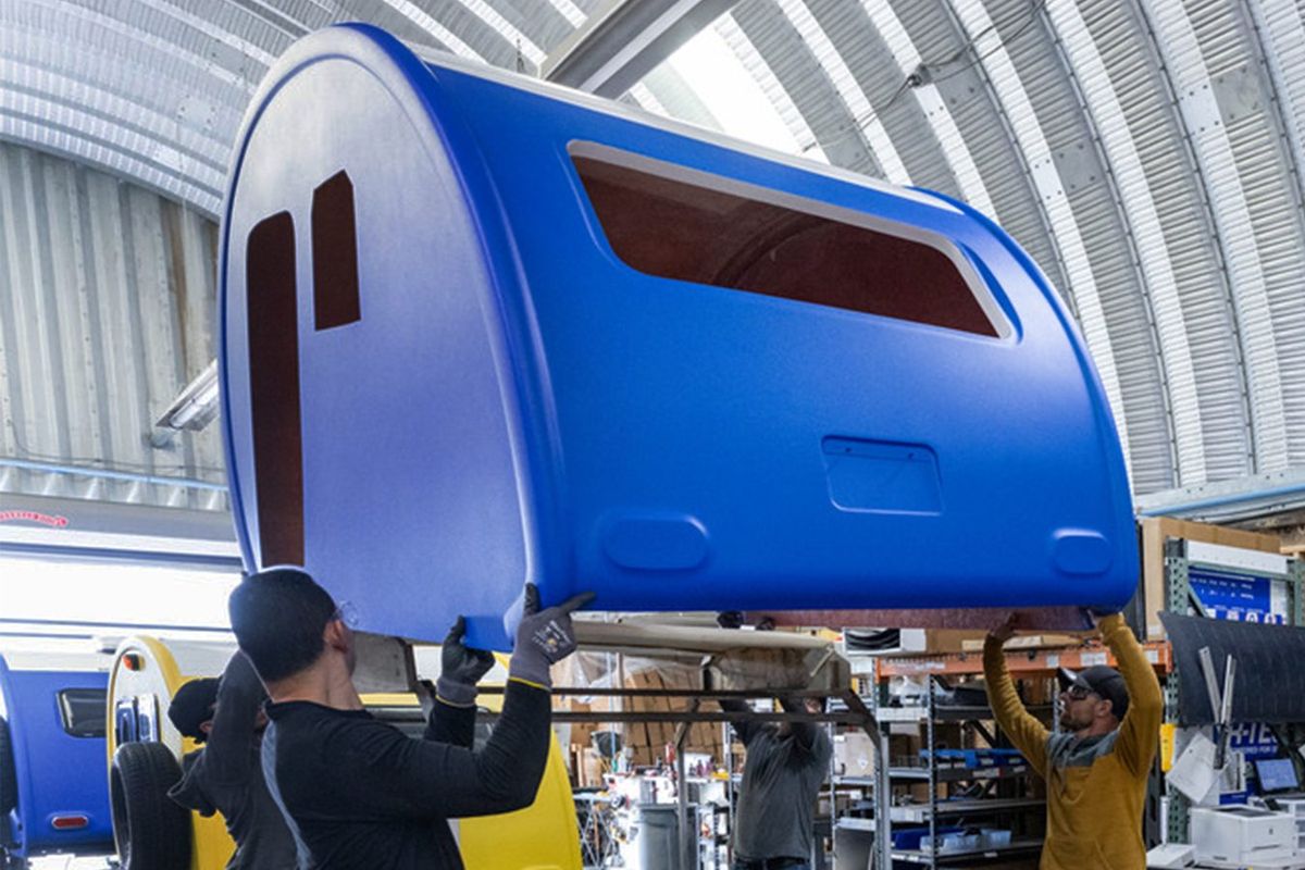 Several team members lifting a blue fiberglass Bean shell in the plant